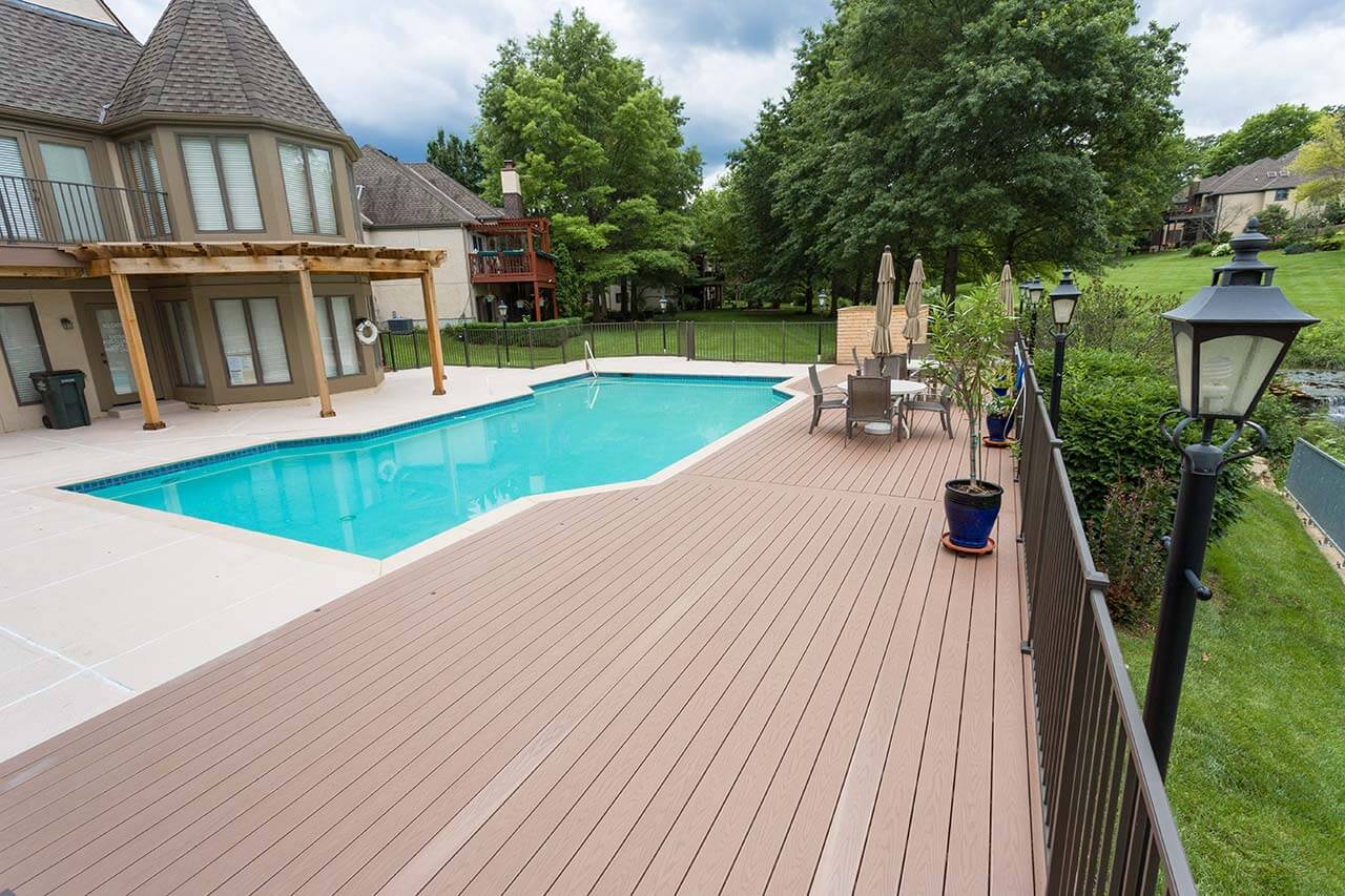 A low composite deck attached to the back of a home surrounding a swimming pool in Leawood KS