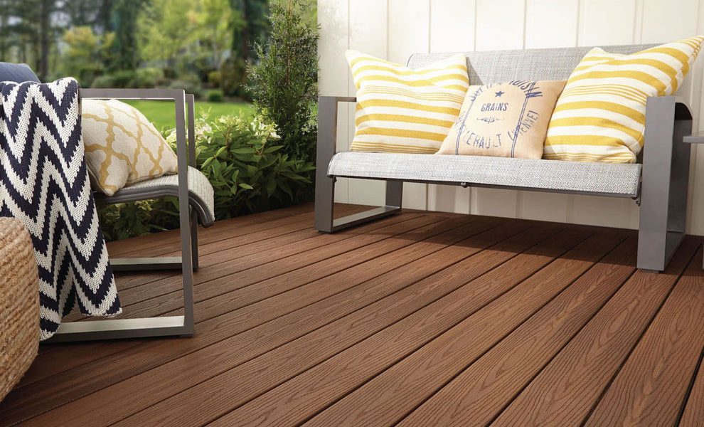 A residential low deck framed by plants featuring modern outdoor seating.